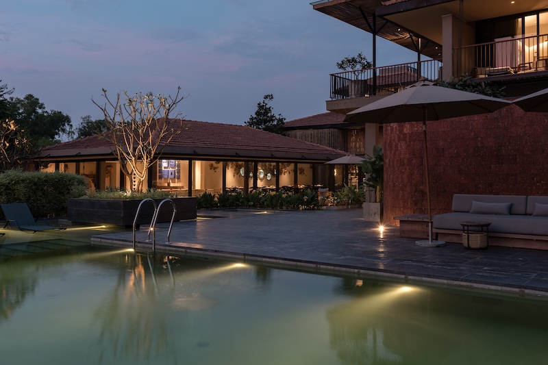 Carefully designed red laterite walls defined a courtyard living and served as a beautiful curvaceous backdrop for the pool. (Image Credit: Amaraanth) 