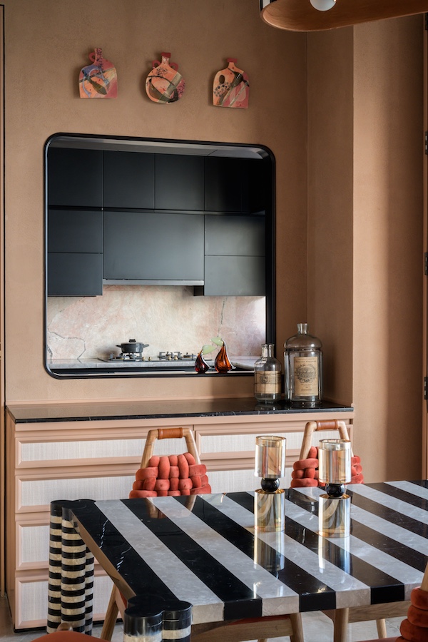 The window with artwork by Kara Sabi allows connectivity with the kitchen. (Image Credits: Wabi Sabi)