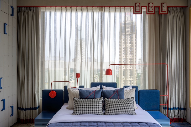 The son’s bedroom features deep blue hues paired with a pop of red. (Image Credits: Wabi Sabi)