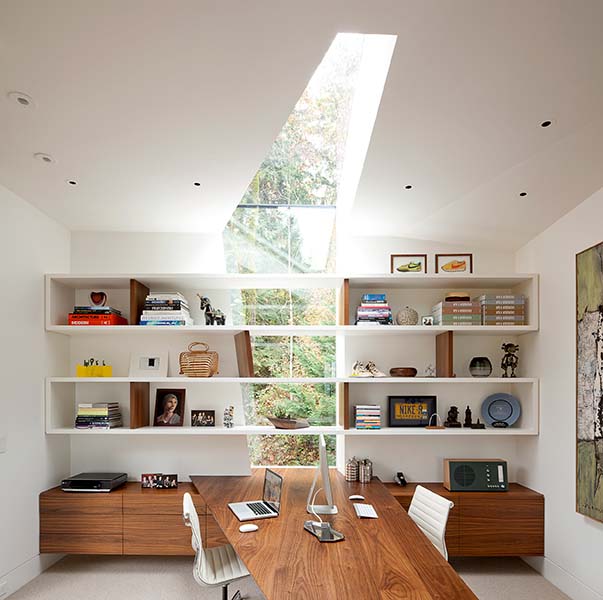 The skylight floods the home office in natural light, highlighting the modern shelving and walnut desk. (Image Credit: Jeremy Bittermann)