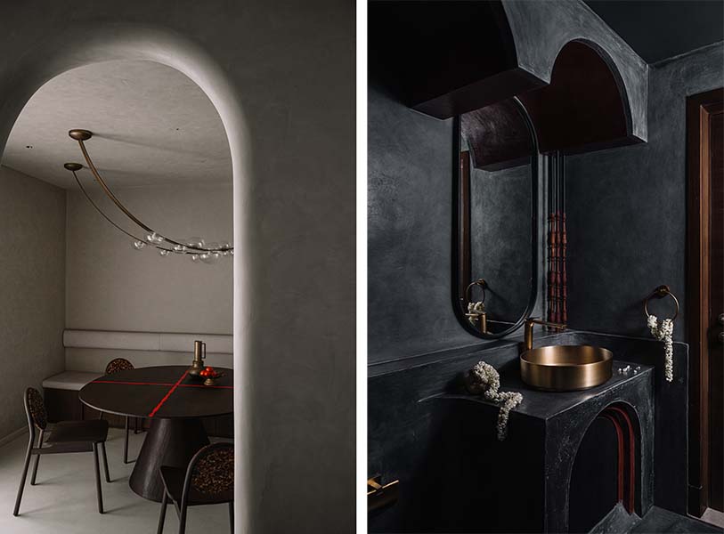 The cosy dining room has a table with a red acrylic cross and intricate carvings from an old wooden bed, dining chairs with a wooden terrazzo backrest, and a ceiling light from Spoon Lighting. The cavernous all-black bathroom features glinting fixtures in oxidised metal. (Image Credit: Ishita Sitwala) 